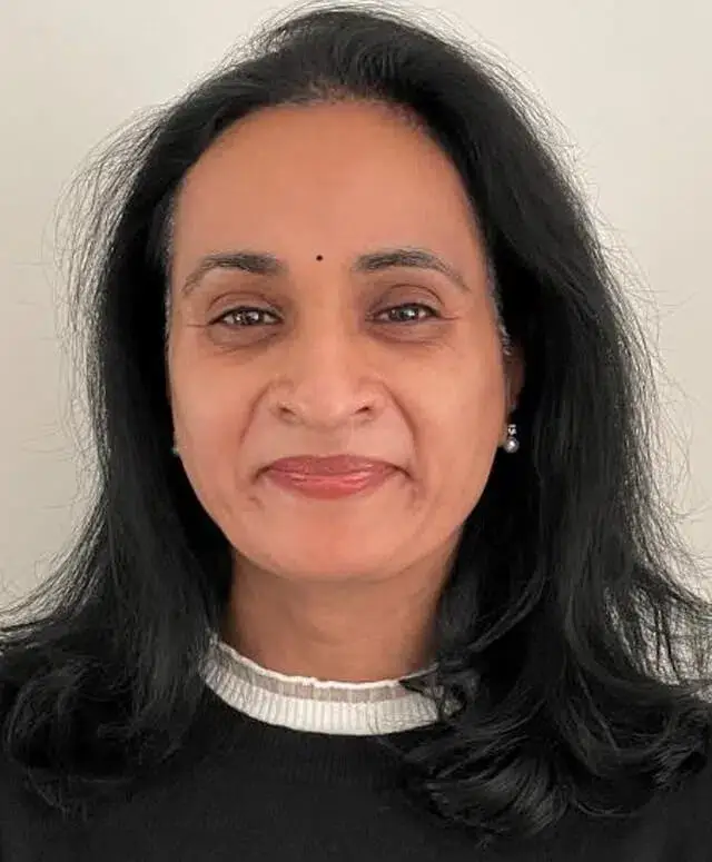 Woman with long dark hair smiling at camera against neutral background, professional headshot