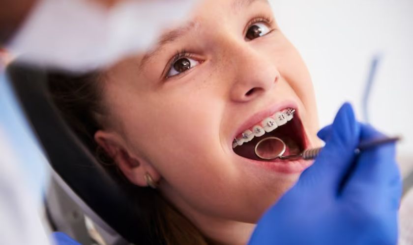 Child receiving dental examination with dentist's gloved hand and mirror in mouth, clinical setting.
