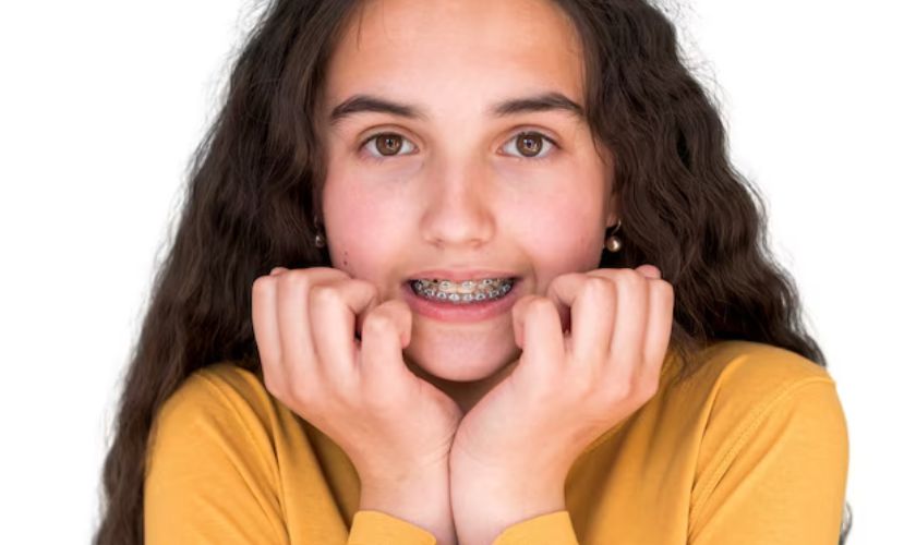Young girl smiling with hands on cheeks wearing yellow shirt against white background