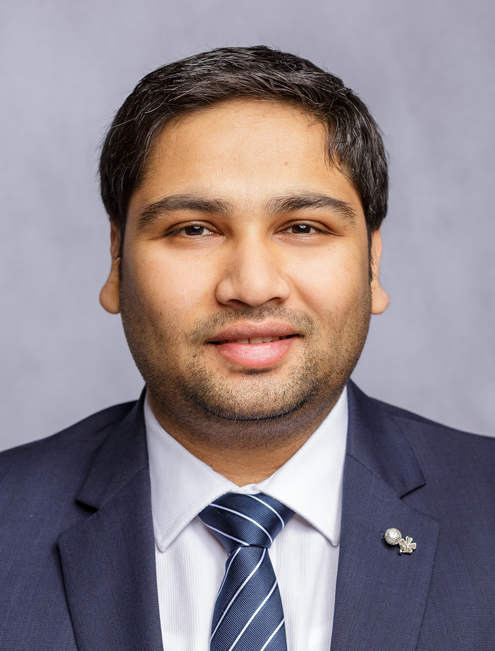 Professional headshot of a man in business attire against a gray background for dental practice.